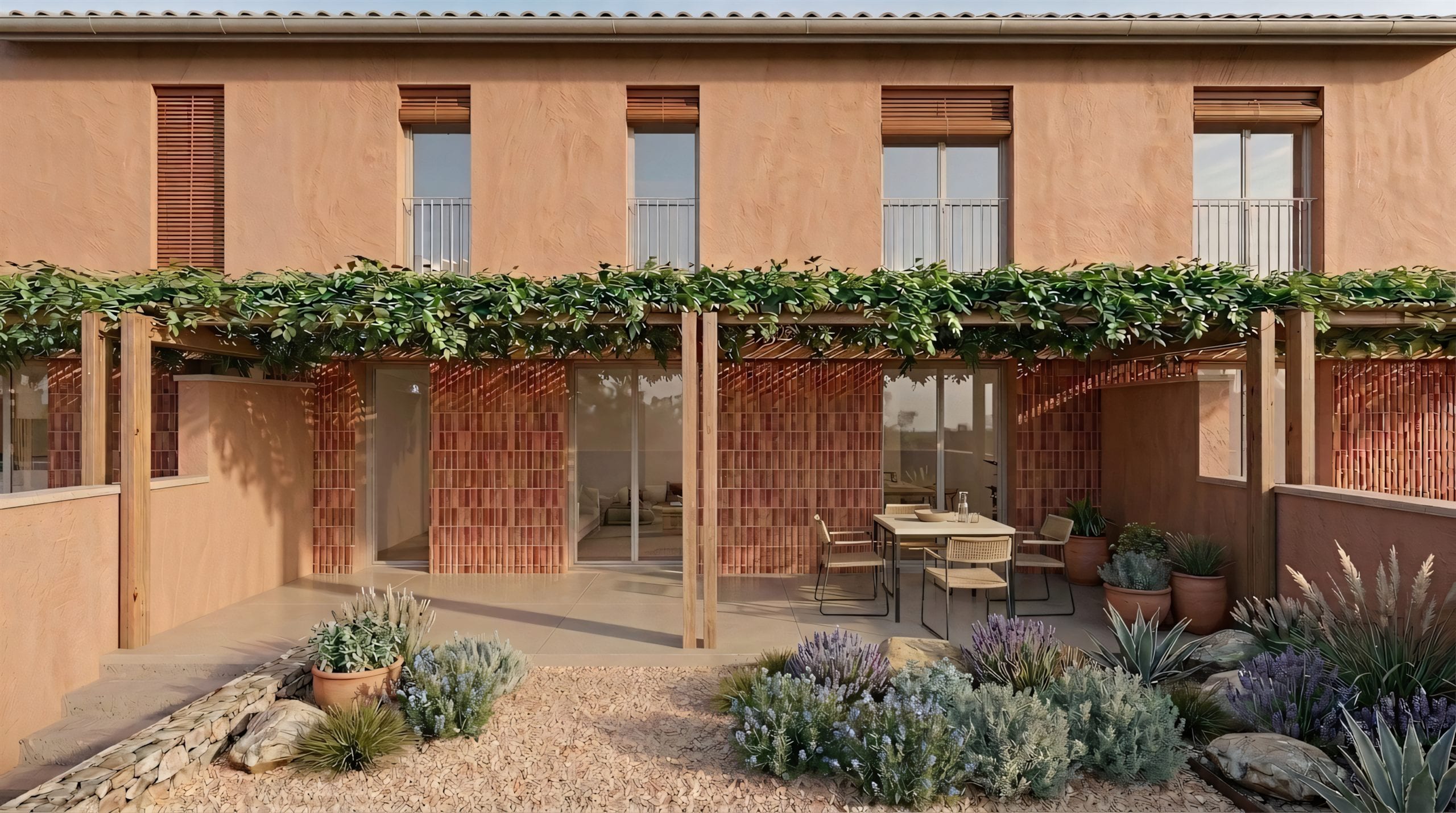 Render del conjunt de dia des del pati: façana de calç rosada, quatre balconeres, pèrgola de fusta amb trepadora i una taula parada a l'exterior. Imatge virtual, subjecte a projecte executiu.